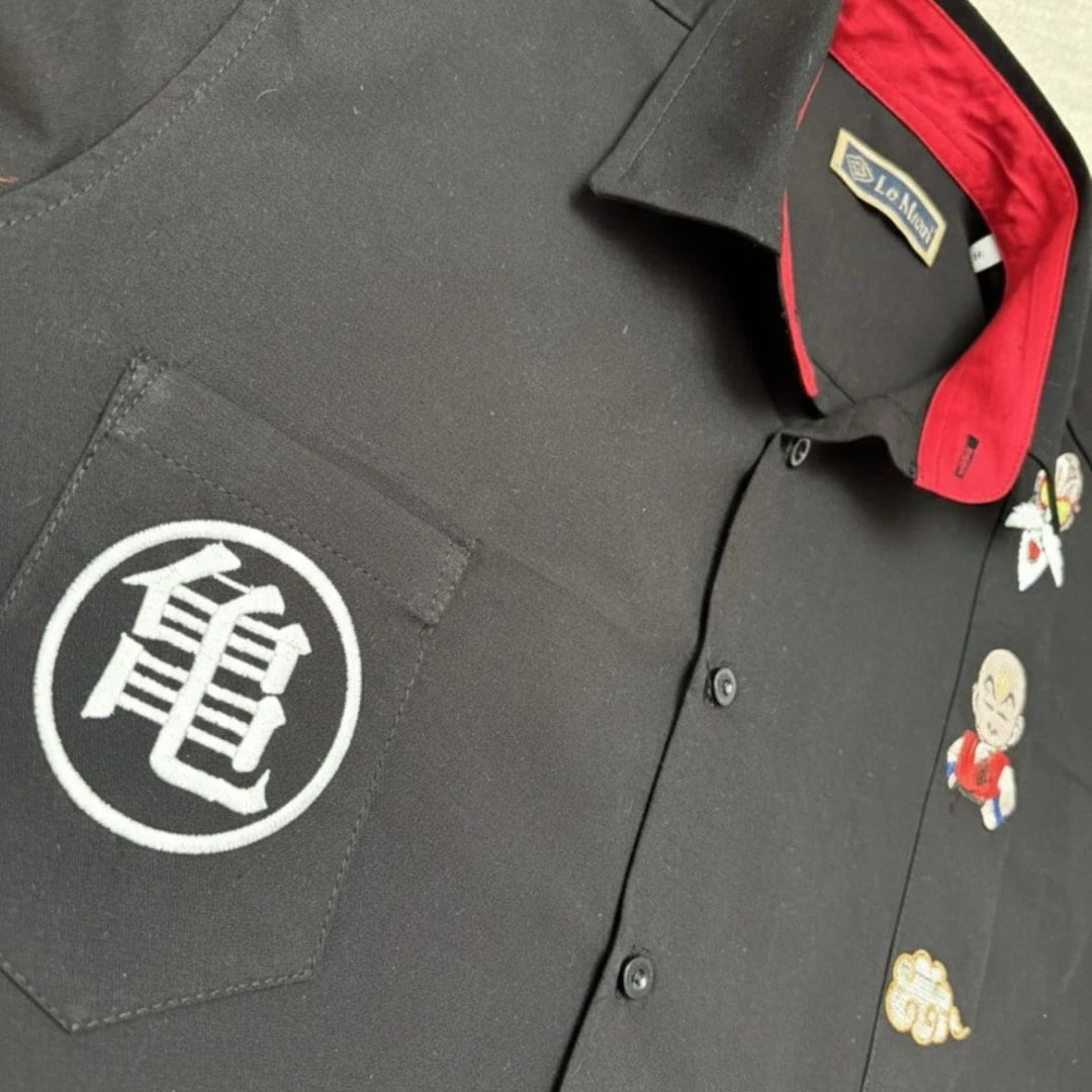 Modelo masculino vistiendo guayabera negra de manga corta en 100% algodón, con bordados frontales inspirados en guerreros de artes marciales y batallas épicas, marca Guayaberas LeMaan.