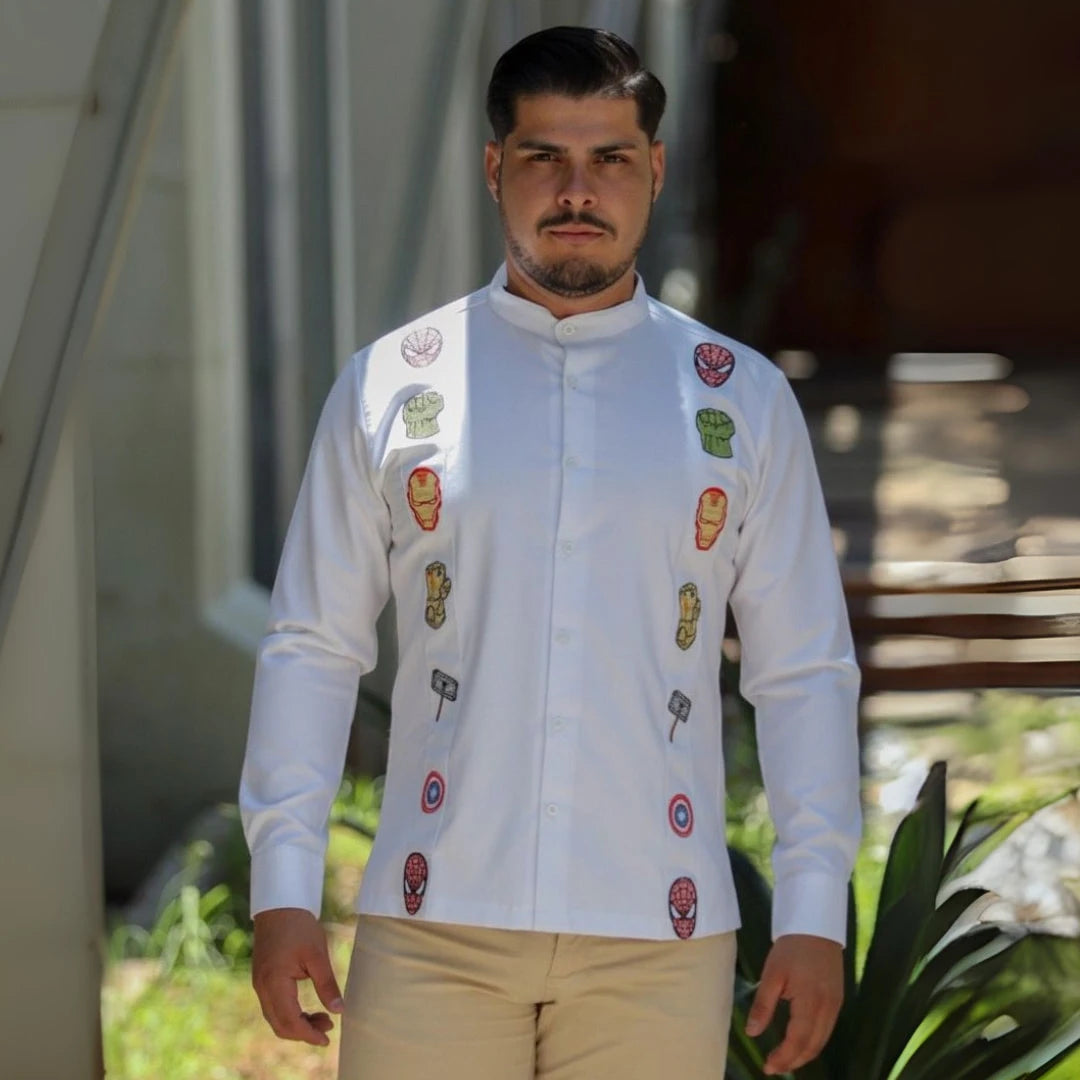 Modelo masculino posando con una guayabera blanca de manga larga en lino y algodón, destacando bordados de símbolos de unión y fuerza inspirados en un universo de héroes legendarios, de Guayaberas LeMaan.