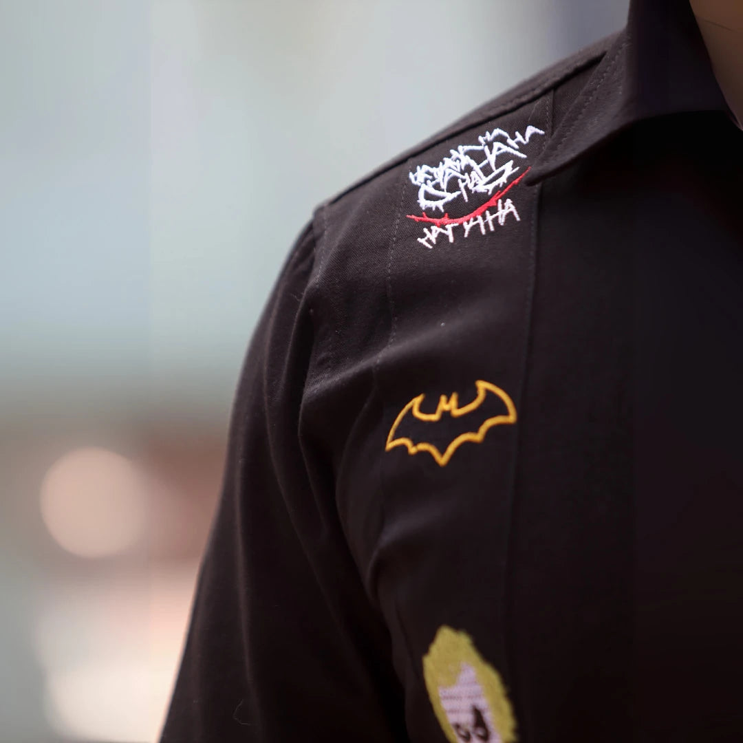 Modelo masculino luciendo guayabera negra de manga corta en 100% algodón, con bordados temáticos inspirados en iconos de la cultura urbana y justicieros nocturnos, diseño exclusivo de Guayaberas LeMaan.