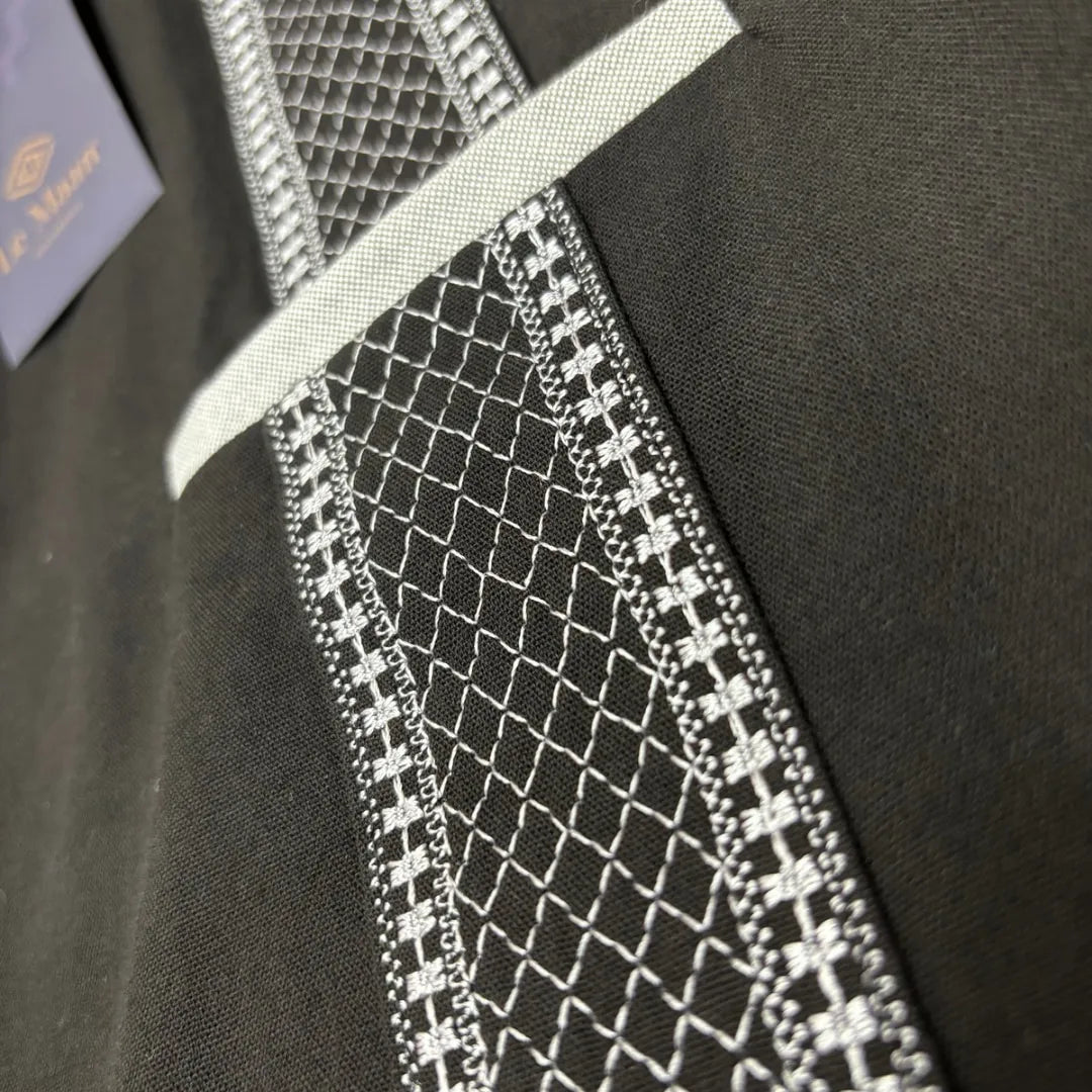 Modelo masculino luciendo una guayabera negra de manga corta y cuello mao de Guayaberas LeMaan, con elegantes detalles en contraste gris y corte contemporáneo.