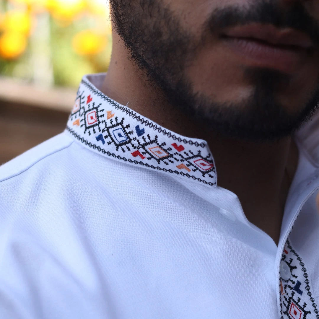Detalle del bordado artesanal en el cuello de la guayabera blanca, resaltando la precisión de la costura y el acabado elegante de la prenda.