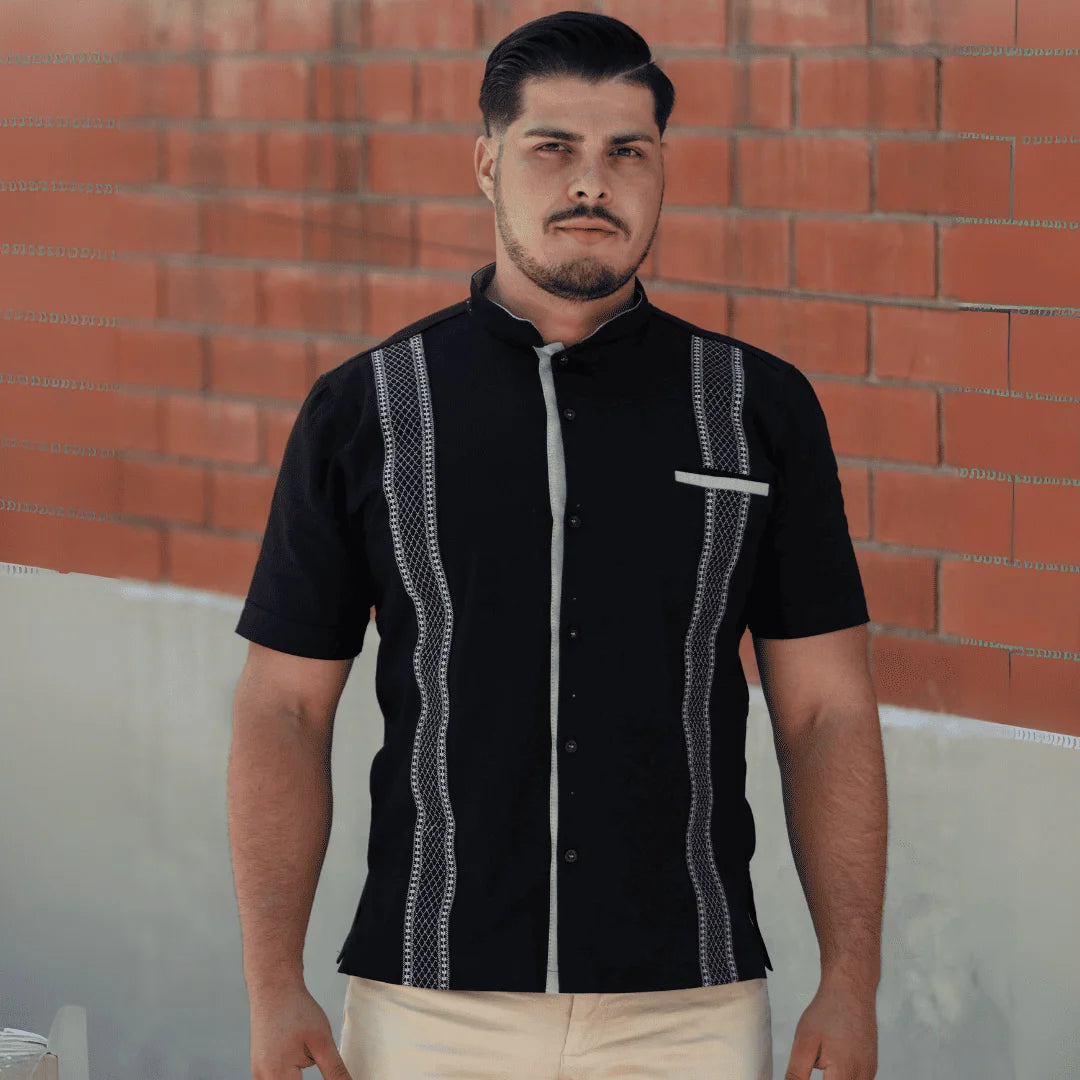 Modelo masculino luciendo una guayabera negra de manga corta y cuello mao de Guayaberas LeMaan, con elegantes detalles en contraste gris y corte contemporáneo.